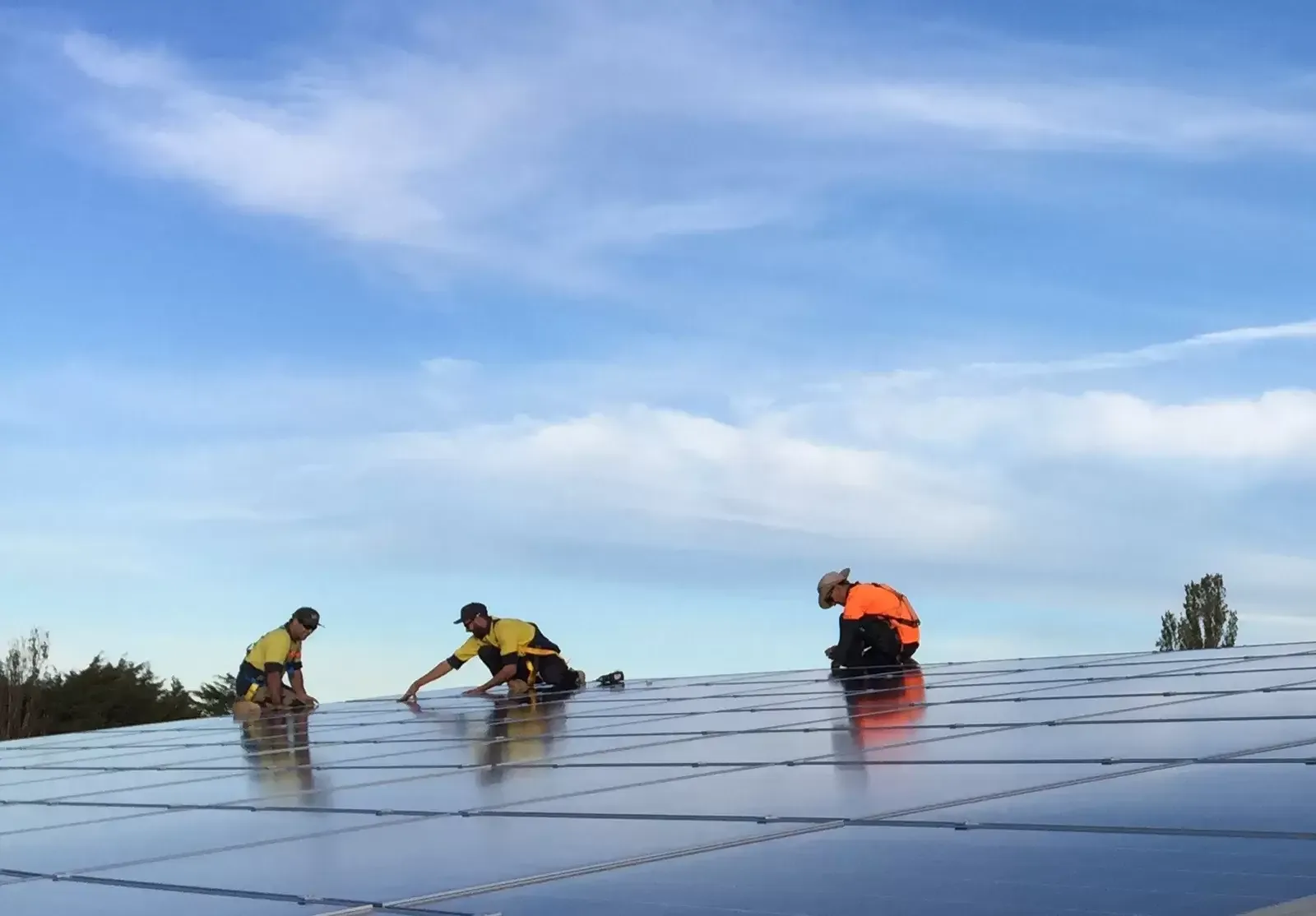 Installers working across a rooftop solar array